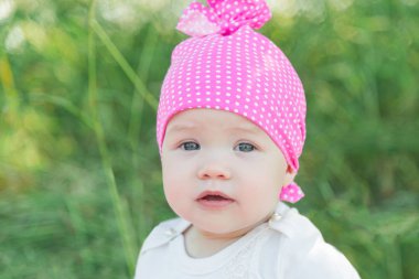 Gülümseyen çocuk çim pembe şapkalı. Şapka polka noktaları. Yeşil çim. Gülümseyen çocuk.