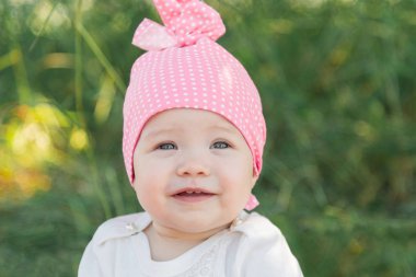 Gülümseyen çocuk çim pembe şapkalı. Şapka polka noktaları. Yeşil çim. Gülümseyen çocuk.