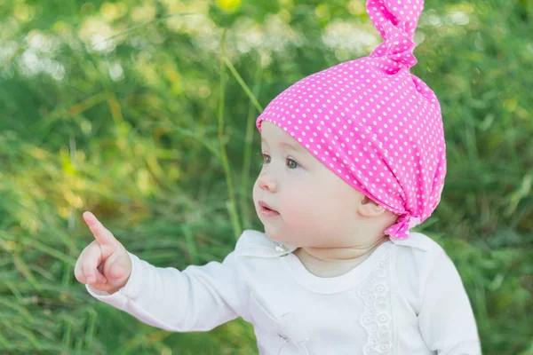 Gülümseyen çocuk çim pembe şapkalı. Şapka polka noktaları. Yeşil çim. Gülümseyen çocuk.