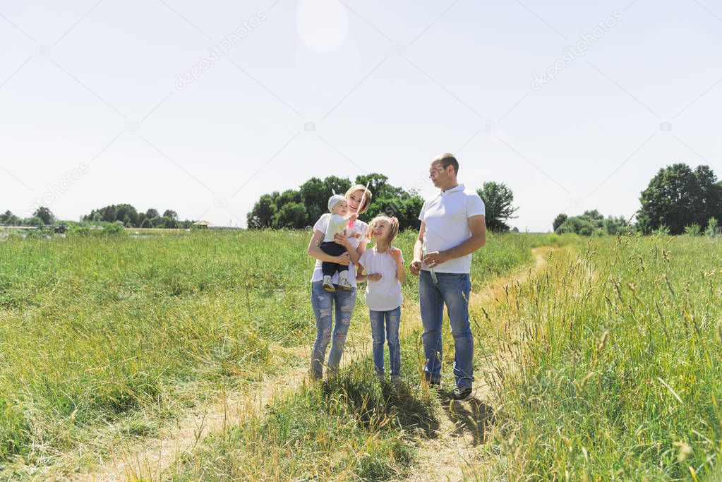 Family walks in the field. With soap bubbles. A family with two children. The family is in the same dress.