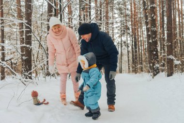 Bir çocuk ile aile yürüyüş. Aile doğada kış aylarında yürür. Doğada kış aile yürüyüş. Kar bir çok.