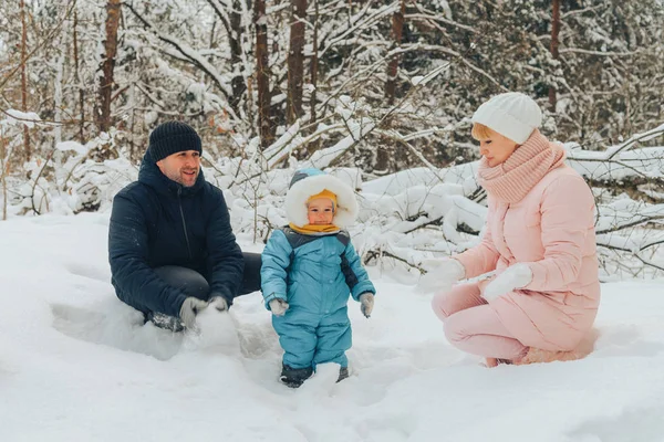 Una famiglia in cammino con un bambino. Passeggiate in famiglia nella natura in inverno. Passeggiata invernale in famiglia nella natura. Un sacco di neve . — Foto Stock