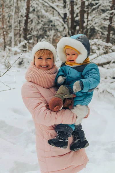 La mamma cammina con il bambino nell'inverno nella natura. Passeggiate in famiglia nella natura in inverno. Foresta invernale. Snow park . — Foto Stock