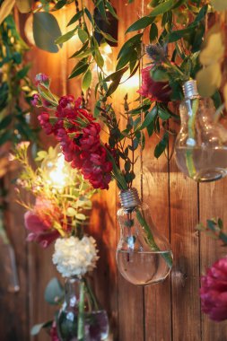 Rustik düğün fotoğraf bölge. El yapımı düğün süslemeleri Photo Booth kırmızı çiçekler içerir. Çelenk ve ampulleri