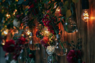 Rustik düğün fotoğraf bölge. El yapımı düğün süslemeleri Photo Booth kırmızı çiçekler içerir. Çelenk ve ampulleri