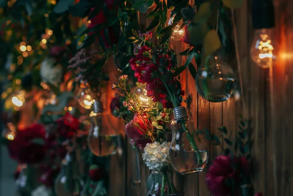 Rustik düğün fotoğraf bölge. El yapımı düğün süslemeleri Photo Booth kırmızı çiçekler içerir. Çelenk ve ampulleri