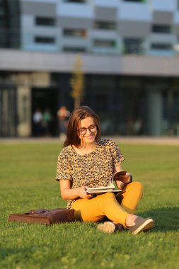 Sırt çantası ve çimenlerin üzerine oturmuş kitap ile gözlüklü genç kız öğrenci. Genç kadın açık havada yemek. Erkek retro bisiklet üzerinde. Genç kadın bir bisiklet ile açık havada yemek.