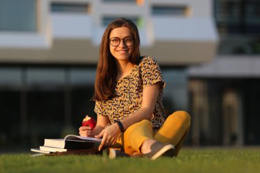 Sırt çantası ve çimenlerin üzerine oturmuş kitap ile gözlüklü genç kız öğrenci. Genç kadın açık havada yemek. Erkek retro bisiklet üzerinde. Genç kadın bir bisiklet ile açık havada yemek.