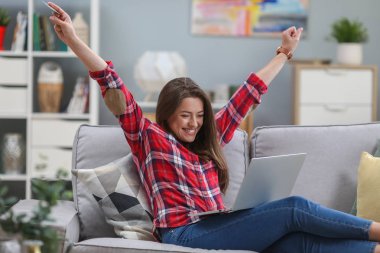 Kredi kartı tutan ve dizüstü bilgisayar kullanan güzel kadın. Online alışveriş kavramı. Kız evde kanepede rahatlatıcı