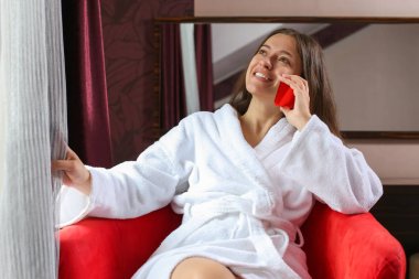 Bir bornoz kırmızı telefon ile sabah otel odasında giymiş güzel kadın portresi. 
