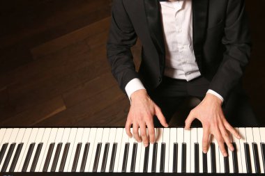 Piyano ellerinde. Piyanist piyano çalıyor. Siyah arka plan üzerine piyano tuşları