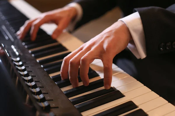 Hands on piano. The pianist plays the piano. Piano keys on black background