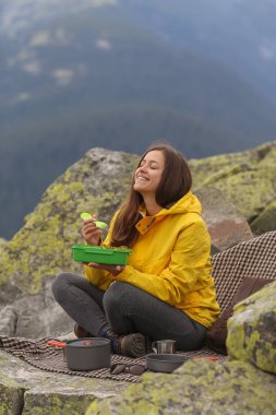 Sarı ceketli genç kadın piknik dağın zirvesinde. 