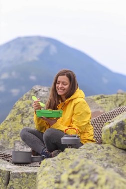 Sarı ceketli genç kadın piknik dağın zirvesinde. 