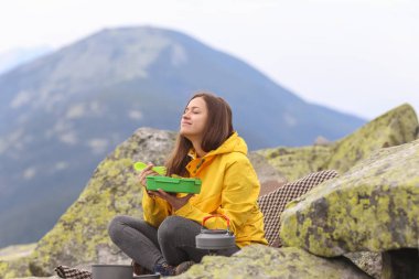 Sarı ceketli genç kadın piknik dağın zirvesinde. 