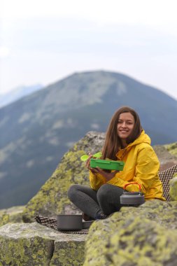Sarı ceketli genç kadın piknik dağın zirvesinde. 