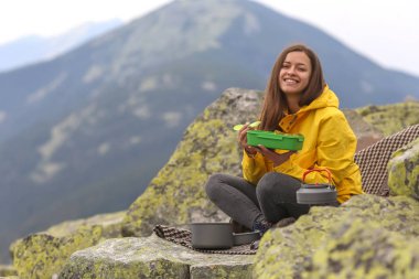 Sarı ceketli genç kadın piknik dağın zirvesinde. 