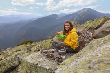 Sarı ceketli genç kadın piknik dağın zirvesinde. 