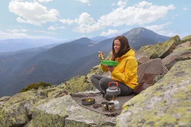 Sarı ceketli genç kadın piknik dağın zirvesinde. 