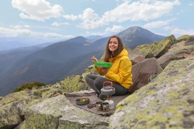 Sarı ceketli genç kadın piknik dağın zirvesinde. 