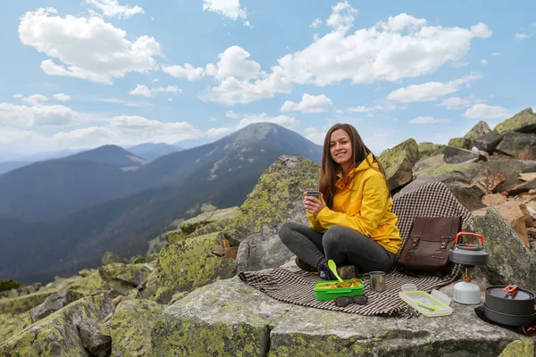 Sarı ceketli genç kadın piknik dağın zirvesinde. 
