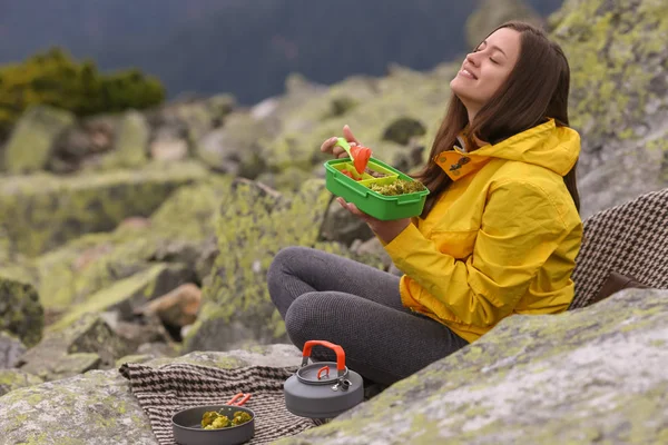 Sarı ceketli genç kadın piknik dağın zirvesinde. 