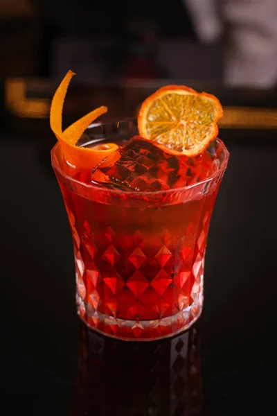 Orange cocktail in retro glass on black background