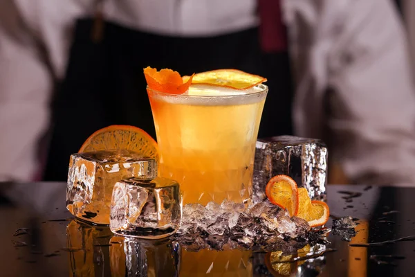 Siyah ayna arka plan üzerinde turuncu dilim ve buz küpleri ile Whiskey ekşi alkol kokteyli adam barmen tarafından yapılan