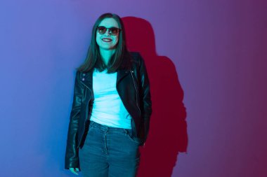 Pembe anf mavi neon ışıkları arka plan koyu gözlük deri ceket moda kız. 
