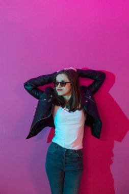 Pembe anf mavi neon ışıkları arka plan koyu gözlük deri ceket moda kız. 