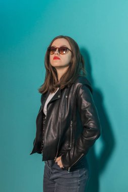 Pembe ve mavi neon ışıkları arka planda koyu gözlük deri ceket moda kız. 