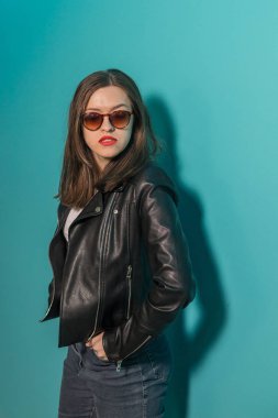 Pembe ve mavi neon ışıkları arka planda koyu gözlük deri ceket moda kız. 