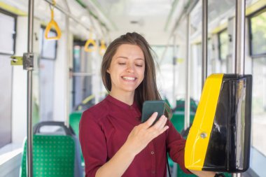 Kadın Kadın tramvayda toplu taşıma için akıllı telefon ile conctactless ödeme. Modern tramvayda sarı bilet makinesi