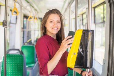 Kadın Kadın tramvayda toplu taşıma için akıllı telefon ile conctactless ödeme. Modern tramvayda sarı bilet makinesi