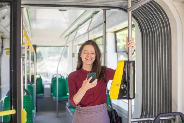 Kadın Kadın tramvayda toplu taşıma için akıllı telefon ile conctactless ödeme. Modern tramvayda sarı bilet makinesi