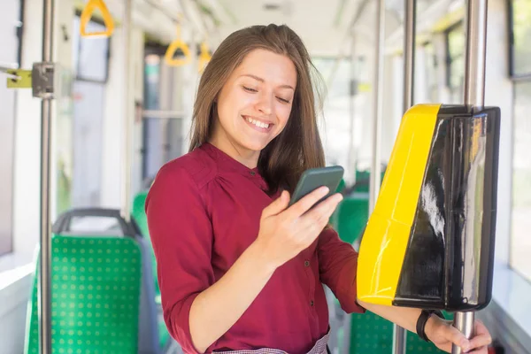 Kadın Kadın tramvayda toplu taşıma için akıllı telefon ile conctactless ödeme. Modern tramvayda sarı bilet makinesi
