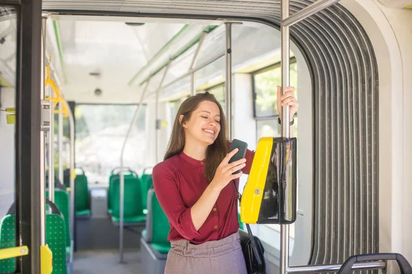 Kadın Kadın tramvayda toplu taşıma için akıllı telefon ile conctactless ödeme. Modern tramvayda sarı bilet makinesi