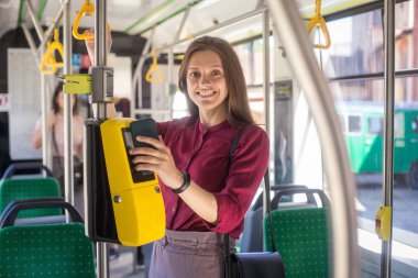 Kadın Kadın tramvayda toplu taşıma için akıllı telefon ile conctactless ödeme. Modern tramvayda sarı bilet makinesi