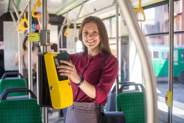 路面電車の公共交通機関のためにスマートフォンでコンクタクティレスを支払う女性 現代のトラムの黄色いチケットマシン — ストック写真