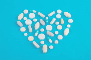 Çeşitli ilaç hapları, haplar ve kapsüller mavi arka planda.