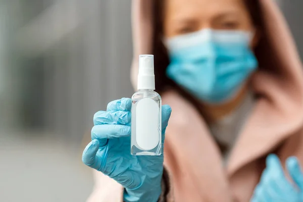 Woman is disinfecting hands with spray sanitizer to prevent coronavirus outdoors