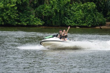 Mutlu genç çift başparmak yukarıya zevk ve sahip eğlenceli bir jet ski üzerinde sürme ile. Tropikal Sri Lanka açıklarındaki