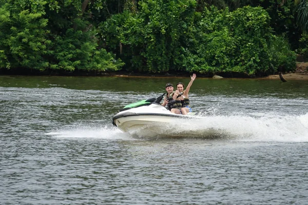Mutlu genç çift başparmak yukarıya zevk ve sahip eğlenceli bir jet ski üzerinde sürme ile. Tropikal Sri Lanka açıklarındaki