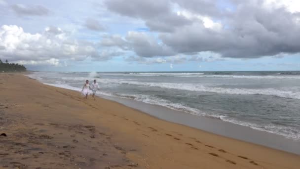 年轻的夫妇在爱运行沿着空的海洋海滩在日落 手牵手 — 图库视频影像