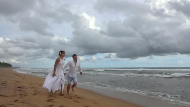 年轻的夫妇在爱在夕阳下沿着空旷的海洋海滩奔跑 手牵手 慢动作 240Fps 的速度拍摄 — 图库视频影像