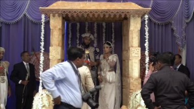 Wadduwa, Sri Lanka - 11 Mayıs 2018: Sri Lanka'da güzel bir düğün töreni. Geleneksel kostümlü yeni evliler kemerin altında duruyorlar. Gelin ve damat ile düğün yeri