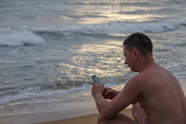 Tropik okyanus sahilinde cep telefonu olan genç adam — Stok fotoğraf