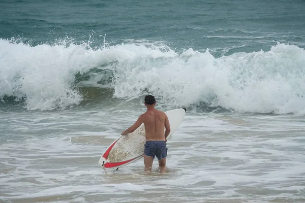 Joven con tabla de surf corriendo en el océano — Foto de Stock