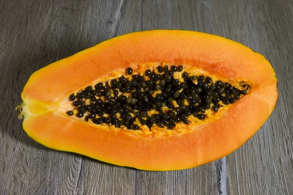 Ahşap bir arka plan üzerinde içinde tohumlar ile taze dilimlenmiş papaya