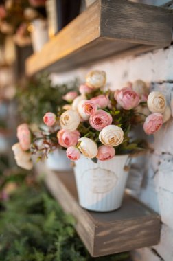 Odanın içindeki metal kovada suni çiçekler.